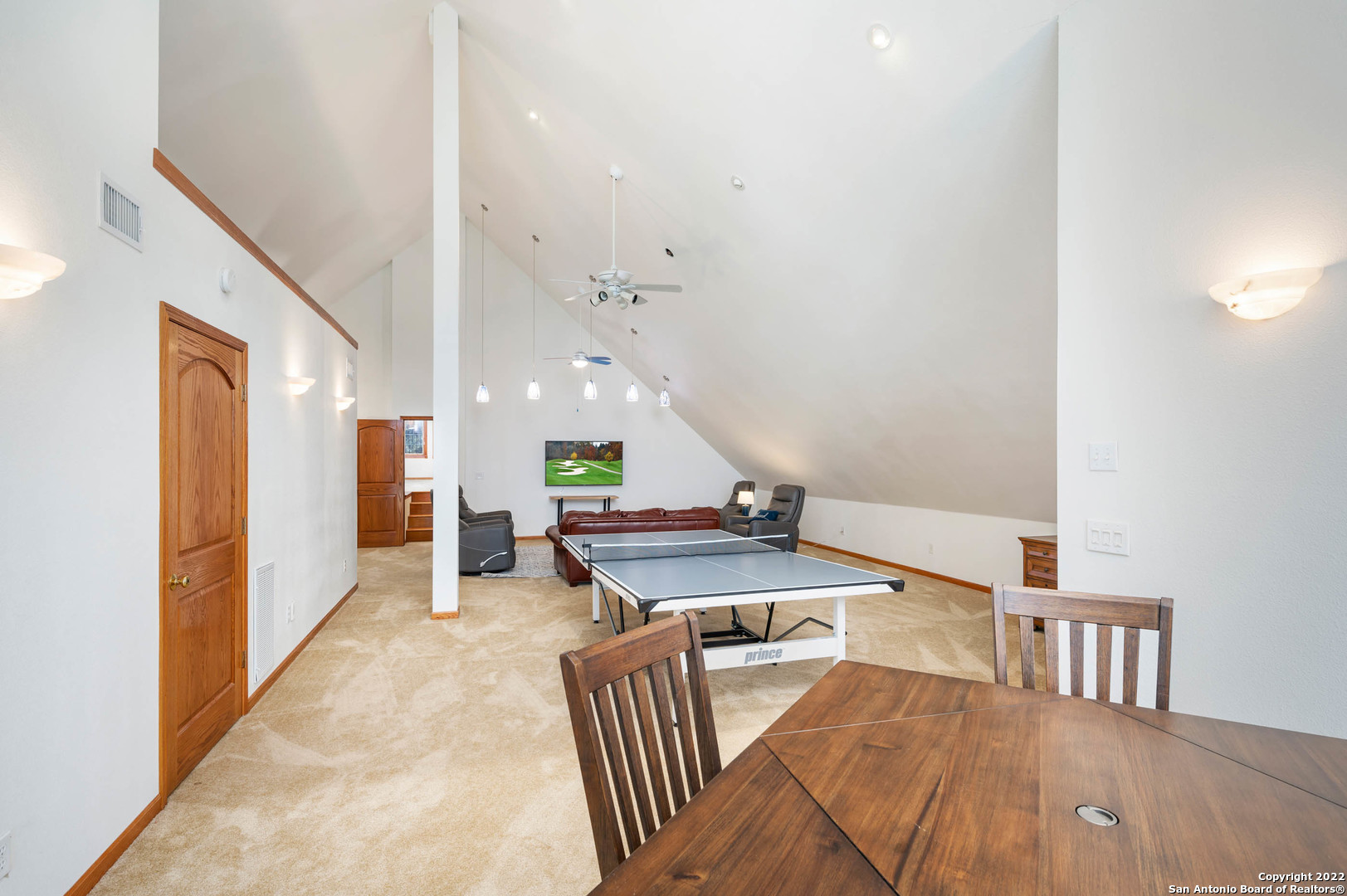 Furnished game room with a ping-pong table, vaulted ceiling, and seating area.