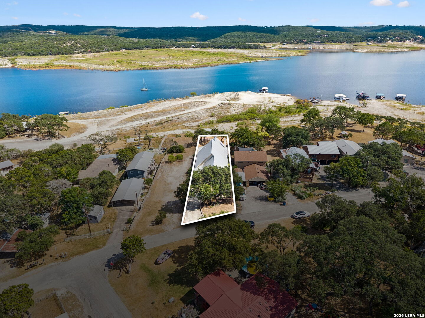 Aerial view of the highlighted waterfront property beside a blue lake and neighboring homes.