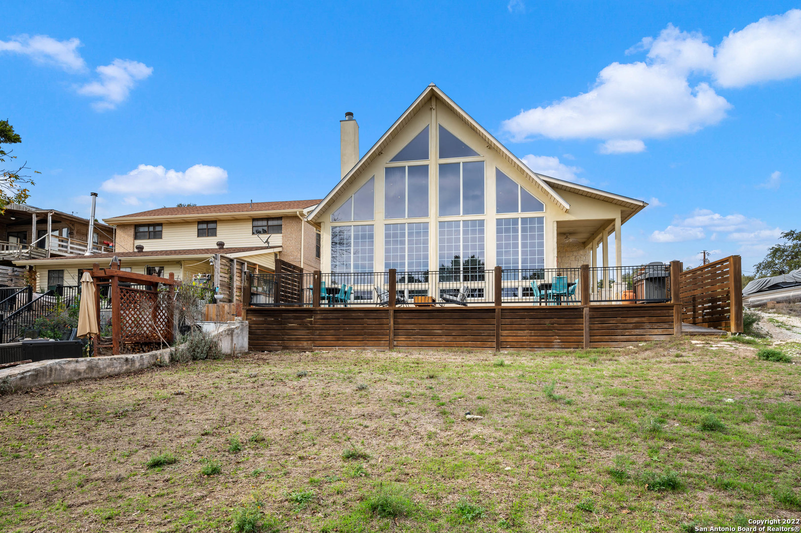 House with a tall glass-fronted gable, raised deck, and wooden privacy fence.