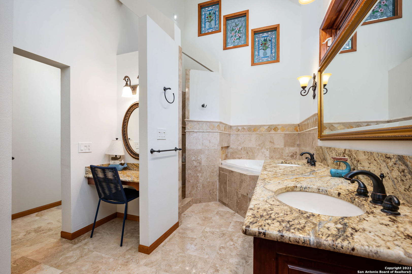 Bathroom with a granite double-sink vanity, built-in tub, makeup alcove, and framed stained-glass panels.