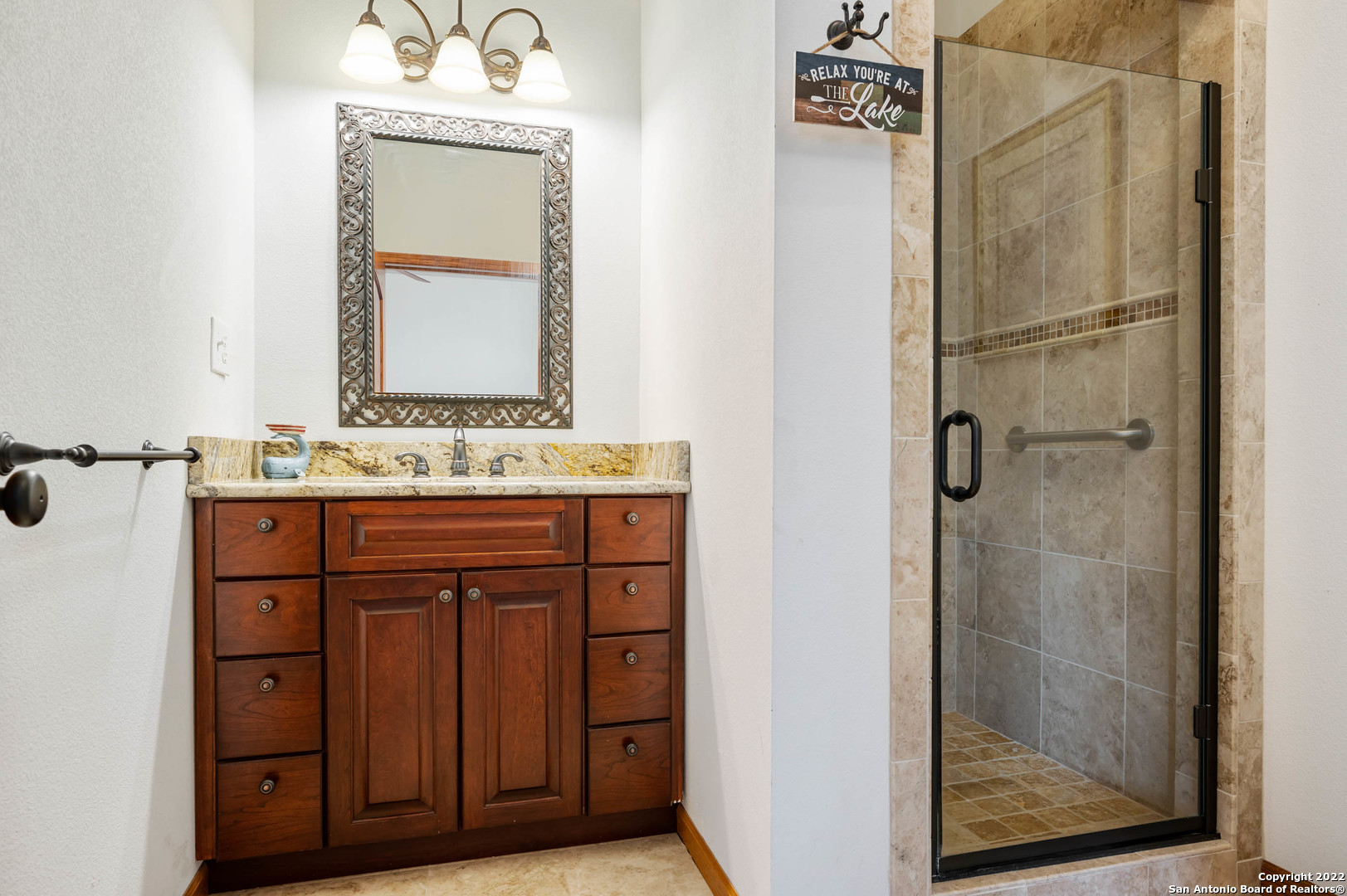 Bathroom with a dark wood vanity and a glass-enclosed, stone-tiled shower.