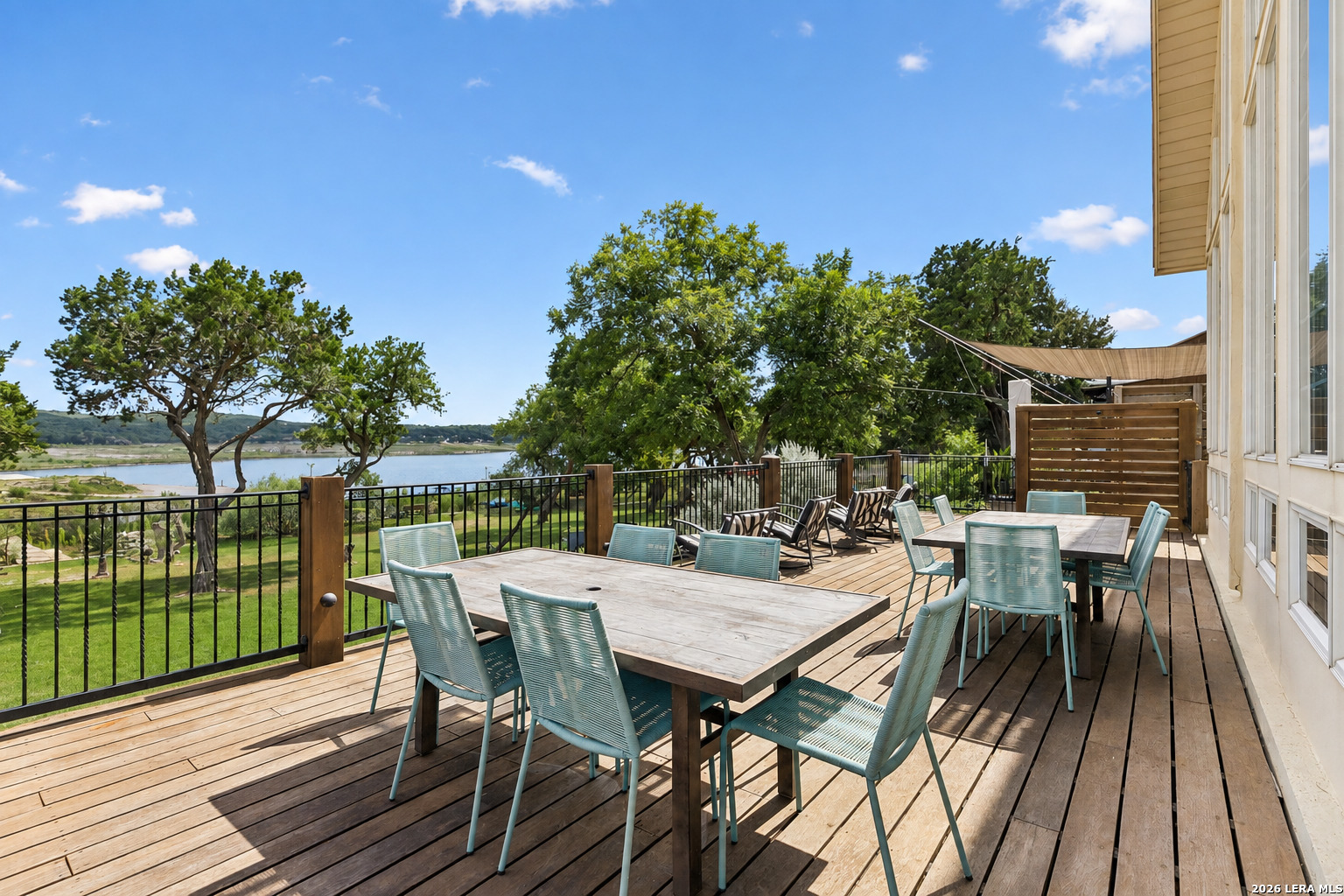 Furnished wooden deck with turquoise chairs overlooking the water.