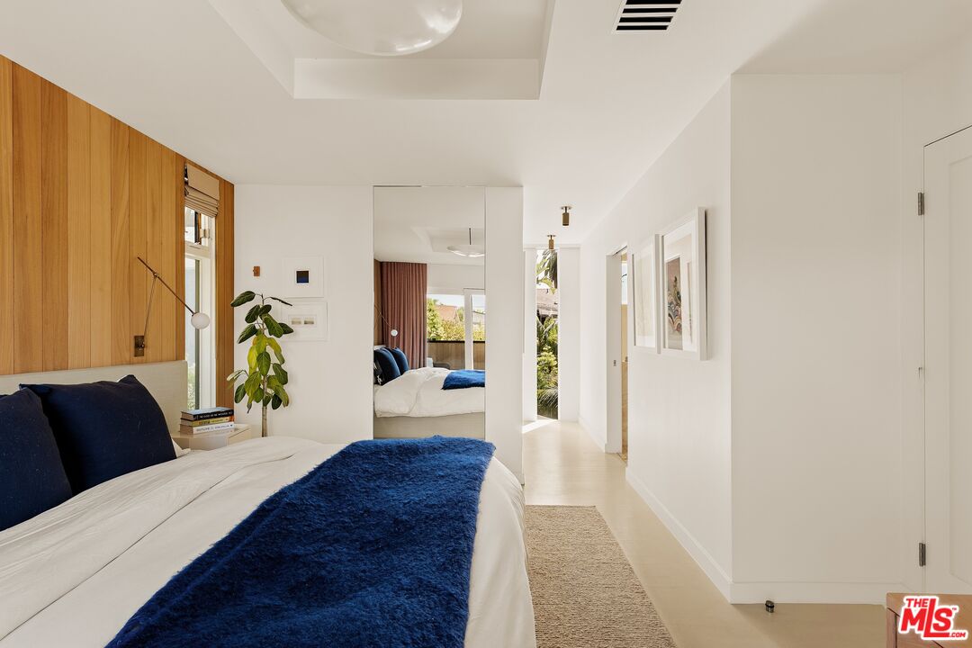 Bedroom with a wood-paneled accent wall, navy pillows, and a deep blue throw across the bed.