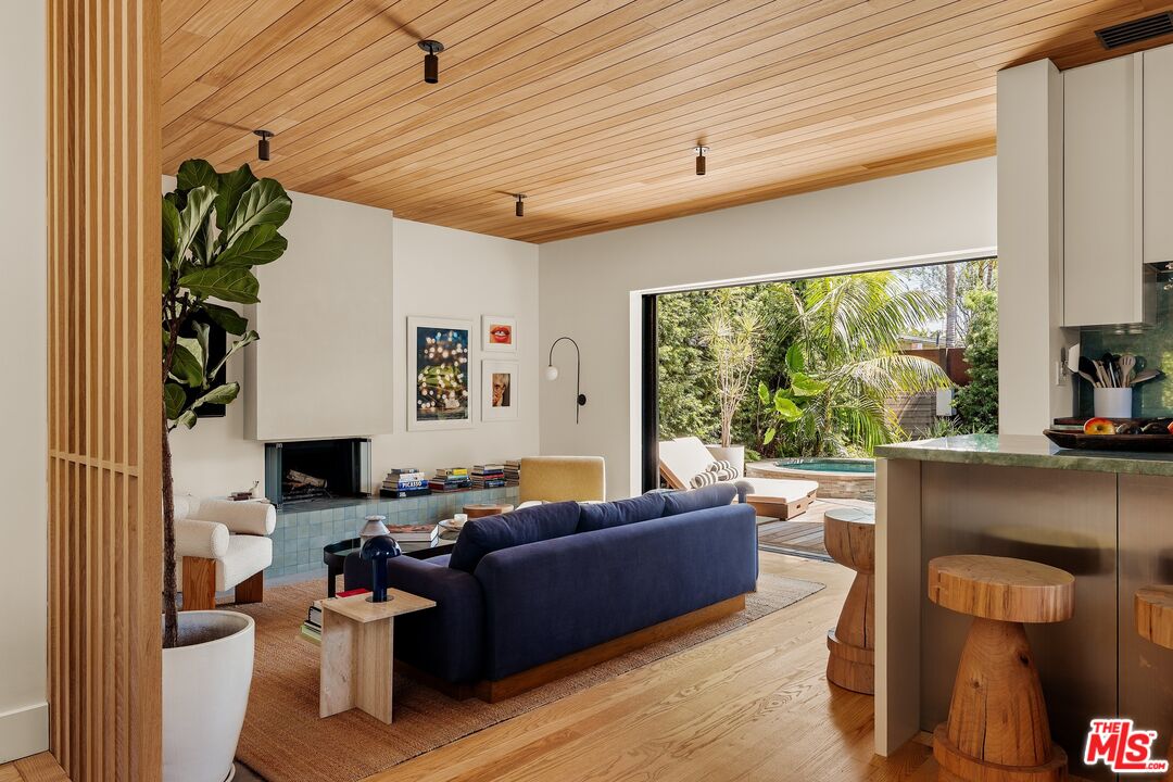 Living room with a wood-plank ceiling, fireplace, and sliding doors opening to a pool patio.