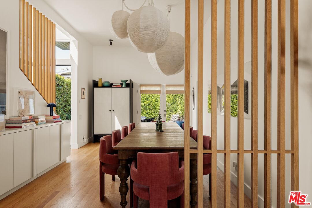 Dining room with a long wood table, red chairs, and sculptural pendant lights.