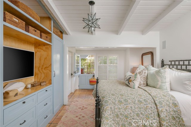 Bedroom with a large floral-covered bed, light blue built-in cabinetry, and shuttered doors.