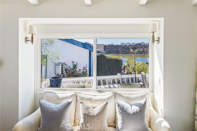 Living room sofa beneath a wide window overlooking a patio, water, and hillside.