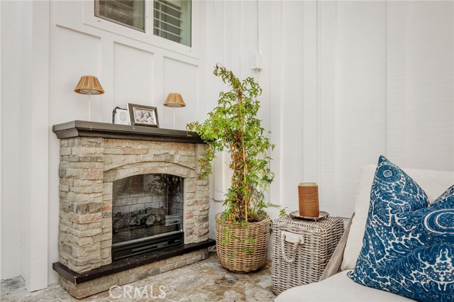 Living room with a stone fireplace, wicker planters, and a blue patterned cushion.