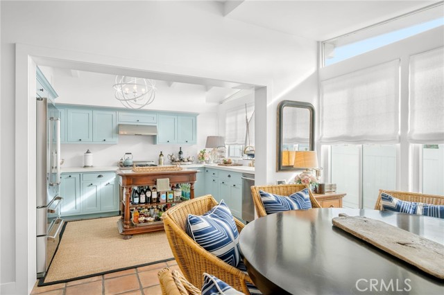 Bright kitchen with pale blue cabinets, a wooden island cart, wicker chairs, and a round dining table.