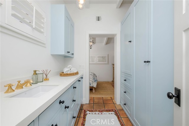 Interior with pale blue built-in cabinets, a long sink counter, terracotta tile floor, and an open doorway.