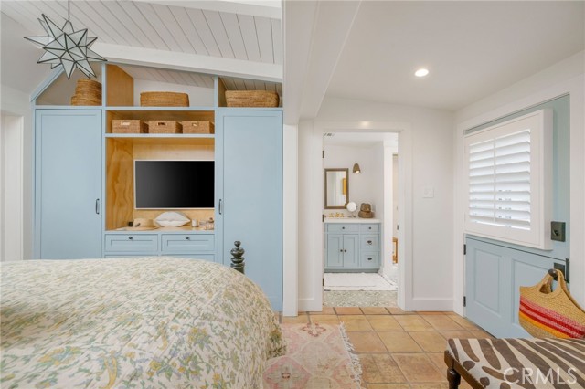 Bedroom with pale blue built-in wardrobe, TV niche, and doorway to a matching vanity.