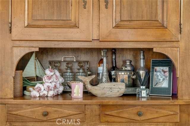 Built-in wooden cabinet with a display shelf decorated with flowers, glassware, and nautical ornaments.
