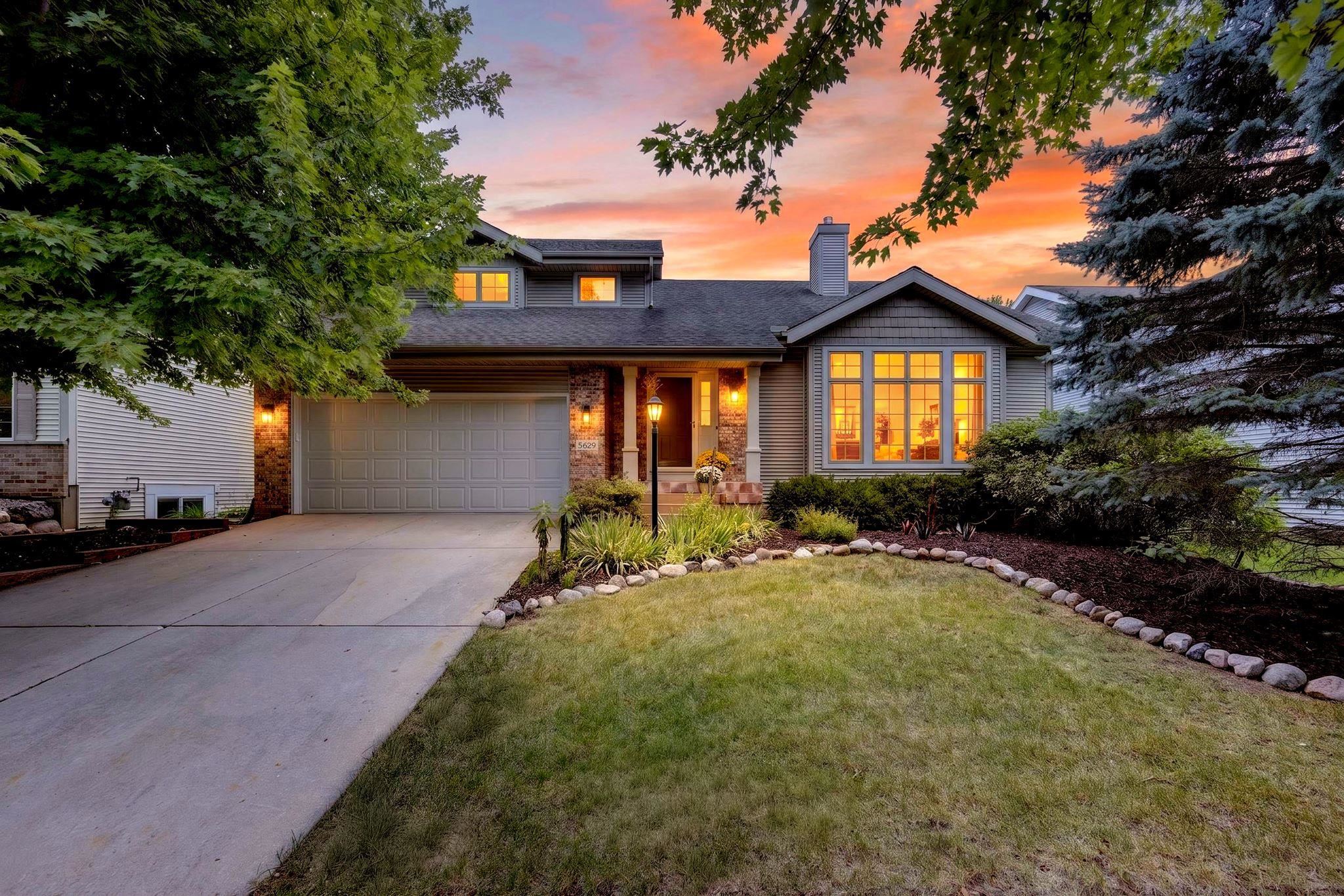 Gray-sided home with brick accents and a two-car garage glowing at sunset.