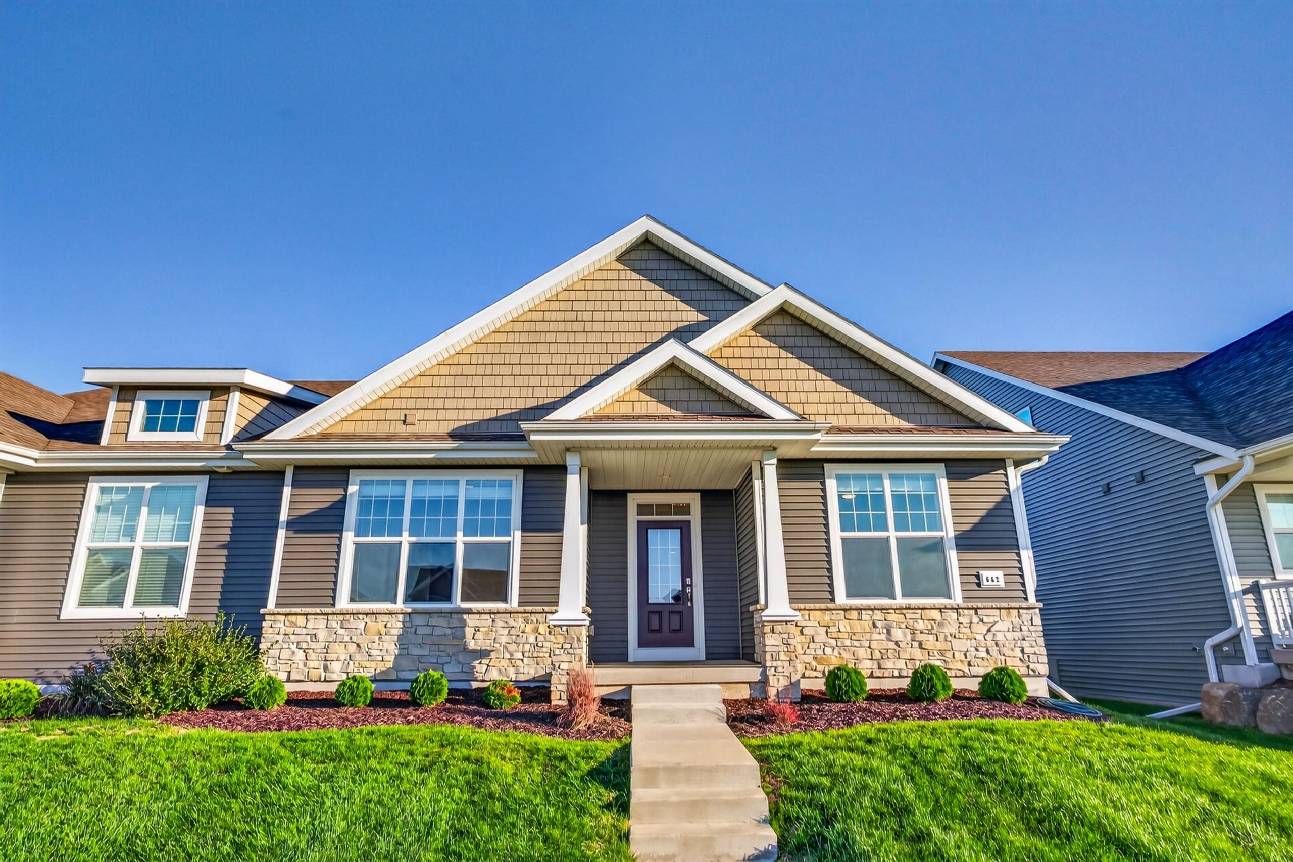 Suburban home with multiple gables, stone veneer, and a landscaped front lawn.