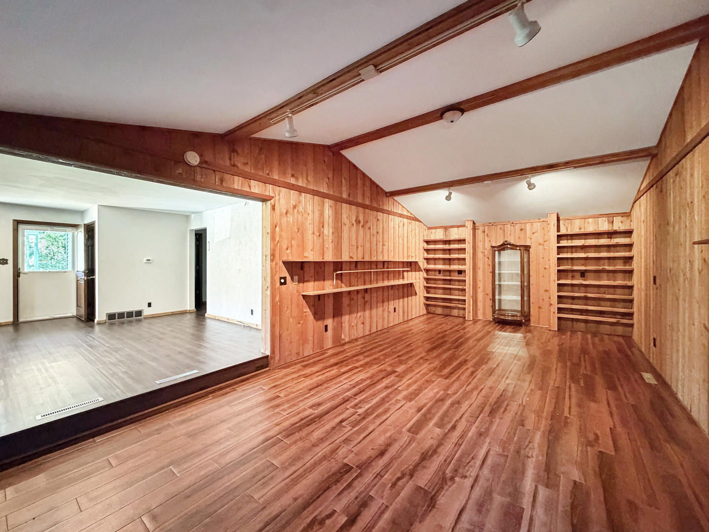 Wood-paneled room with built-in shelves, a glass-front cabinet, and hardwood flooring.