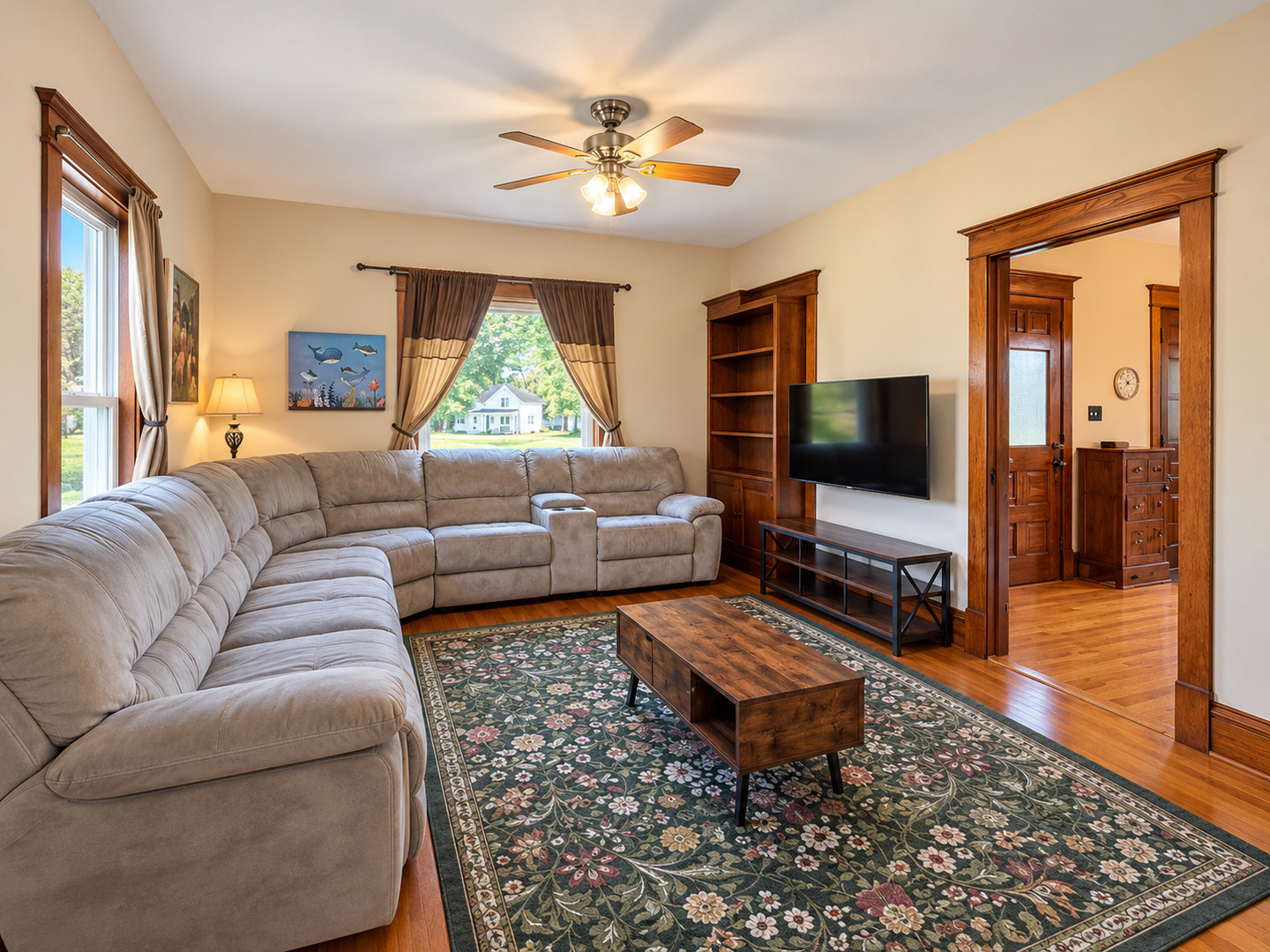 Living room with a curved sectional sofa, floral rug, and dark wood trim.