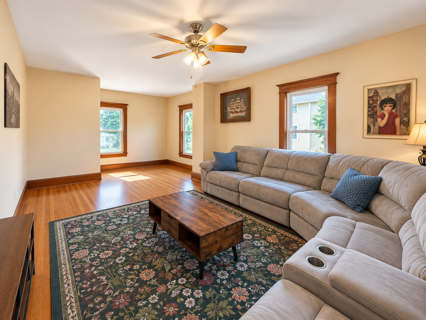 Living room with a sectional sofa, hardwood floors, and a floral rug.