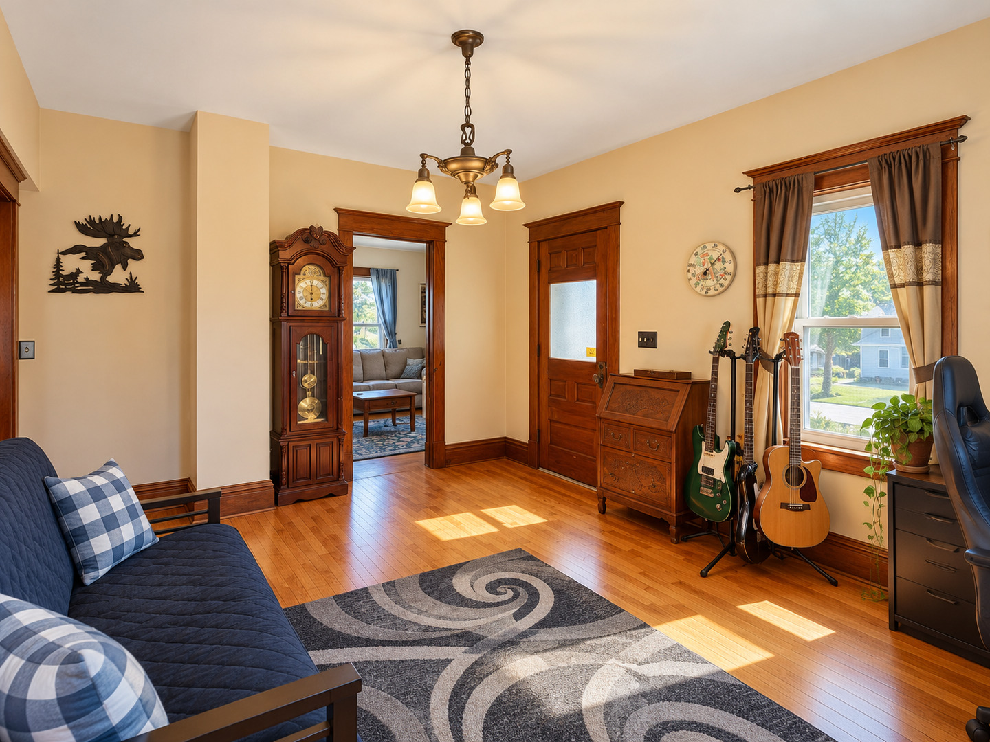 Furnished music room with guitars, a blue sofa, and ornate wood trim.