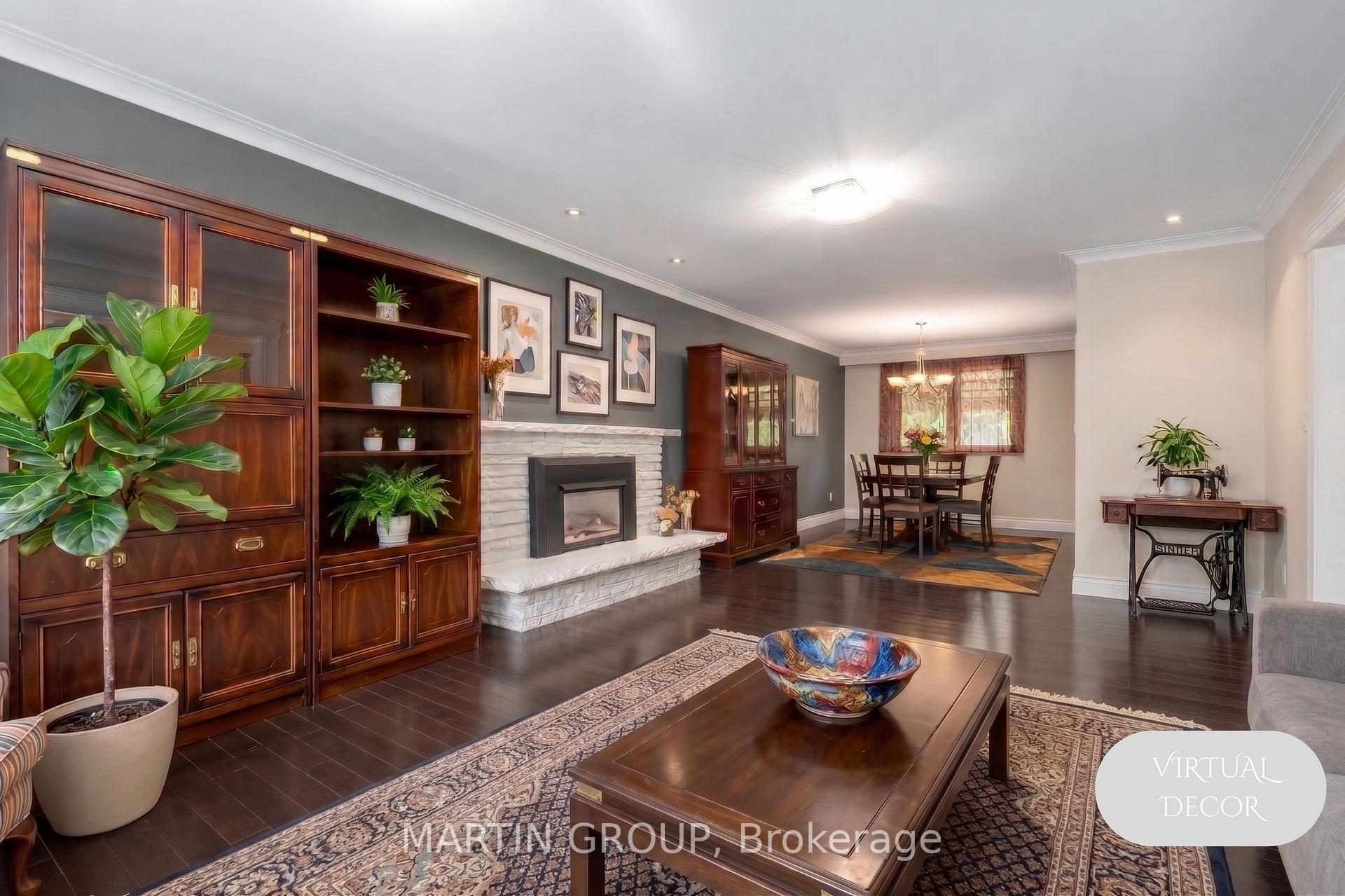 Living room with dark wood cabinetry, a white stone fireplace, and an adjoining dining area.