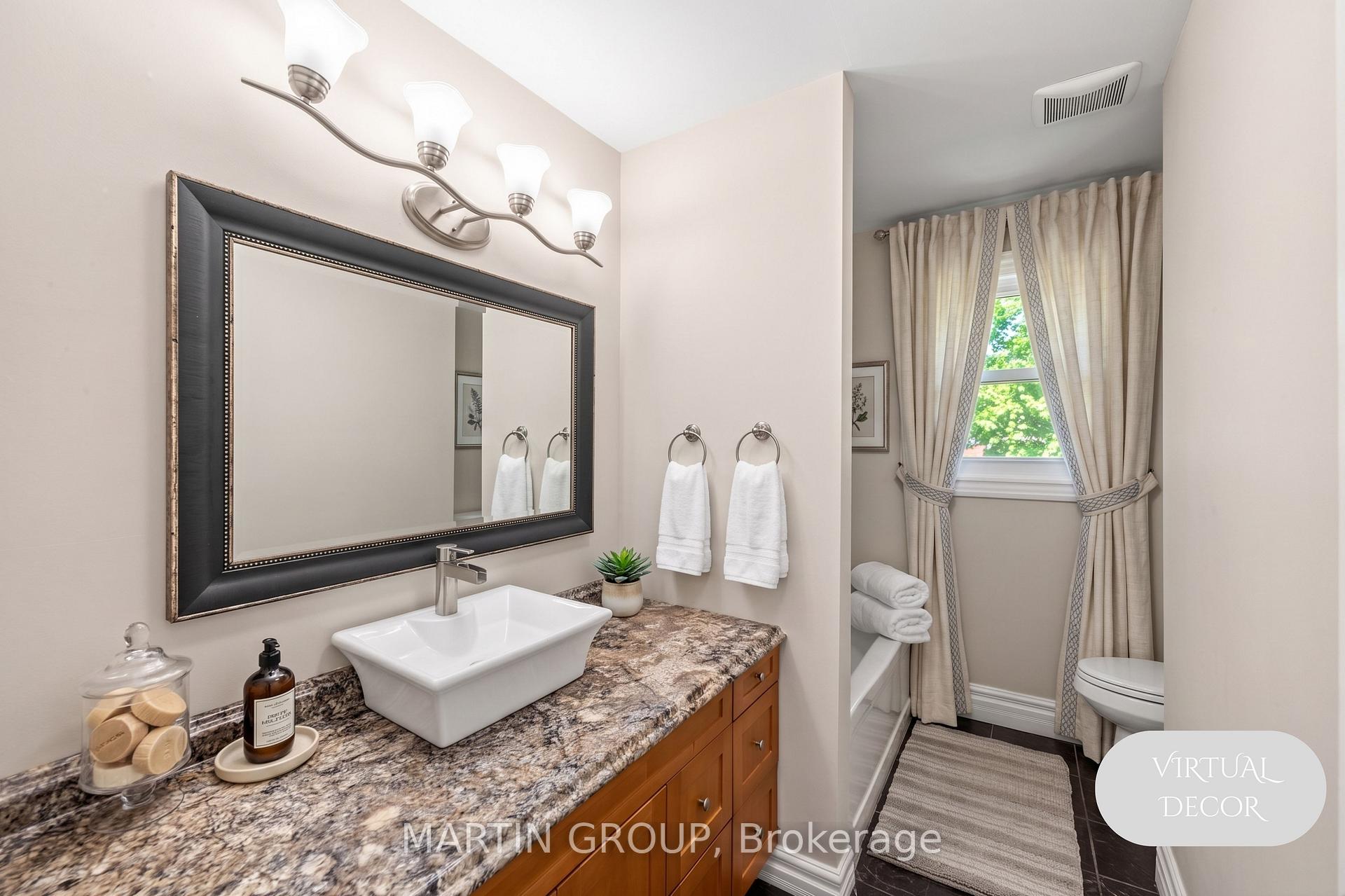 Bathroom with granite vanity, vessel sink, large framed mirror, and curtained window beside the tub.