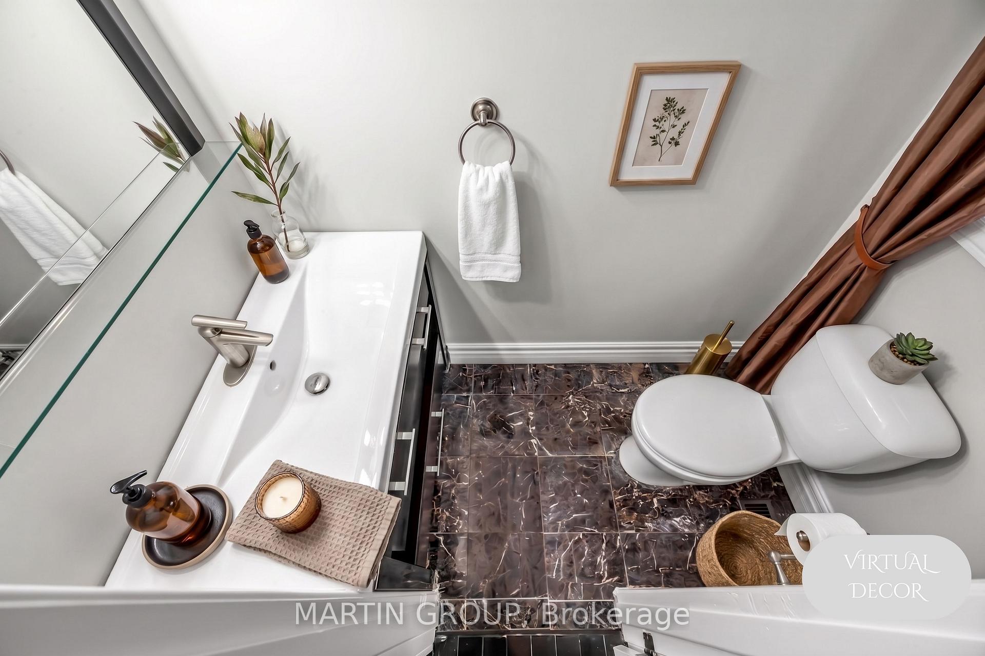 Staged bathroom with a white vanity, toilet, and dark marble-look tile floor.