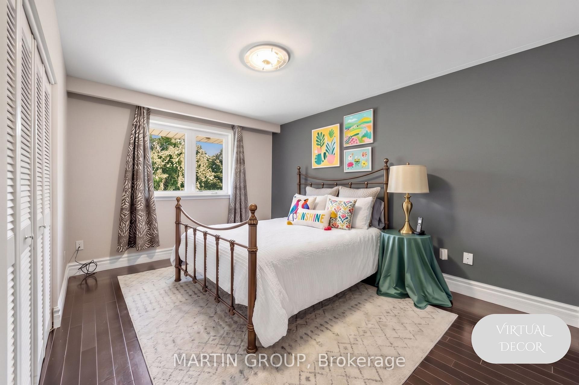 Bedroom with a white bed, bronze metal frame, gray accent wall, and colorful botanical prints.