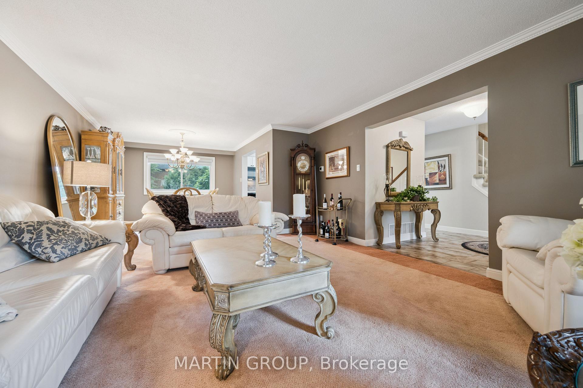 Furnished living room with white sofas, ornate coffee table, and grandfather clock.