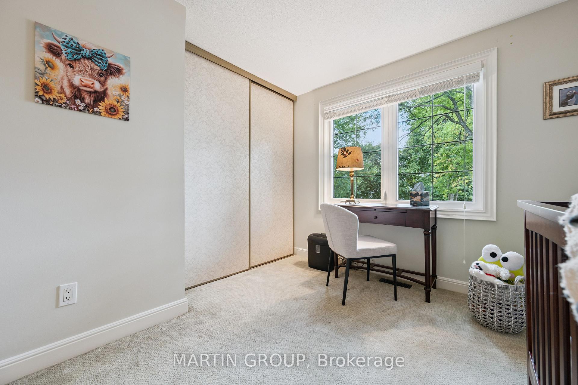 Furnished bedroom with a desk by a large window, sliding closet doors, and a basket of toys.