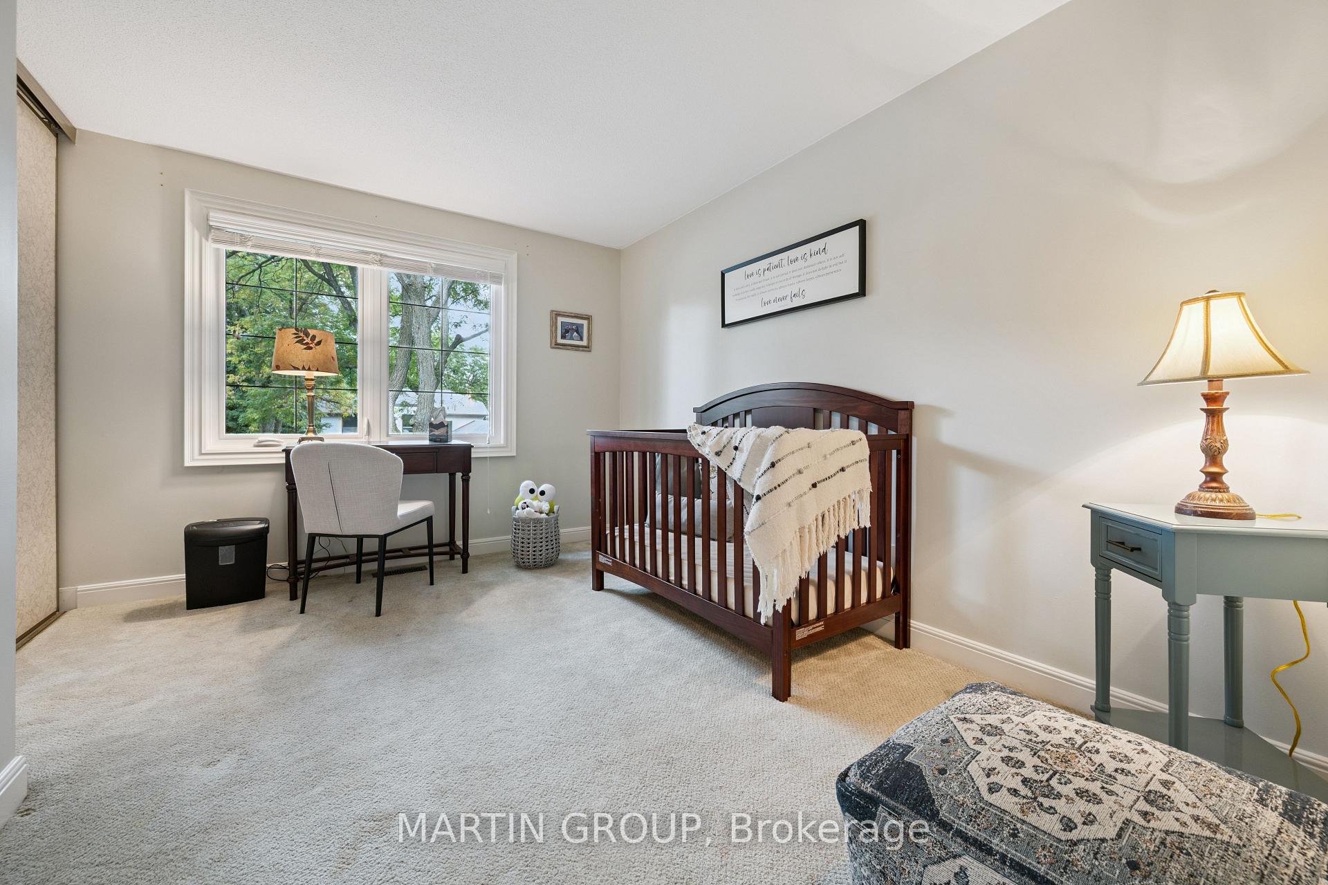 Nursery with a dark wood crib beside a large window and a small desk.