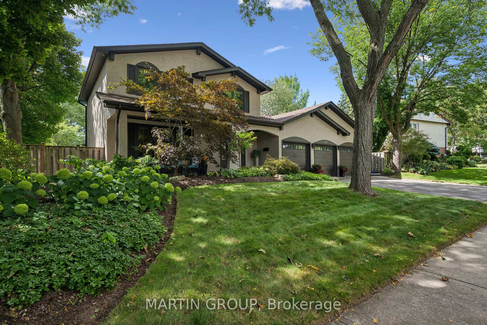 Two-storey stucco home with a three-car garage and landscaped front garden.