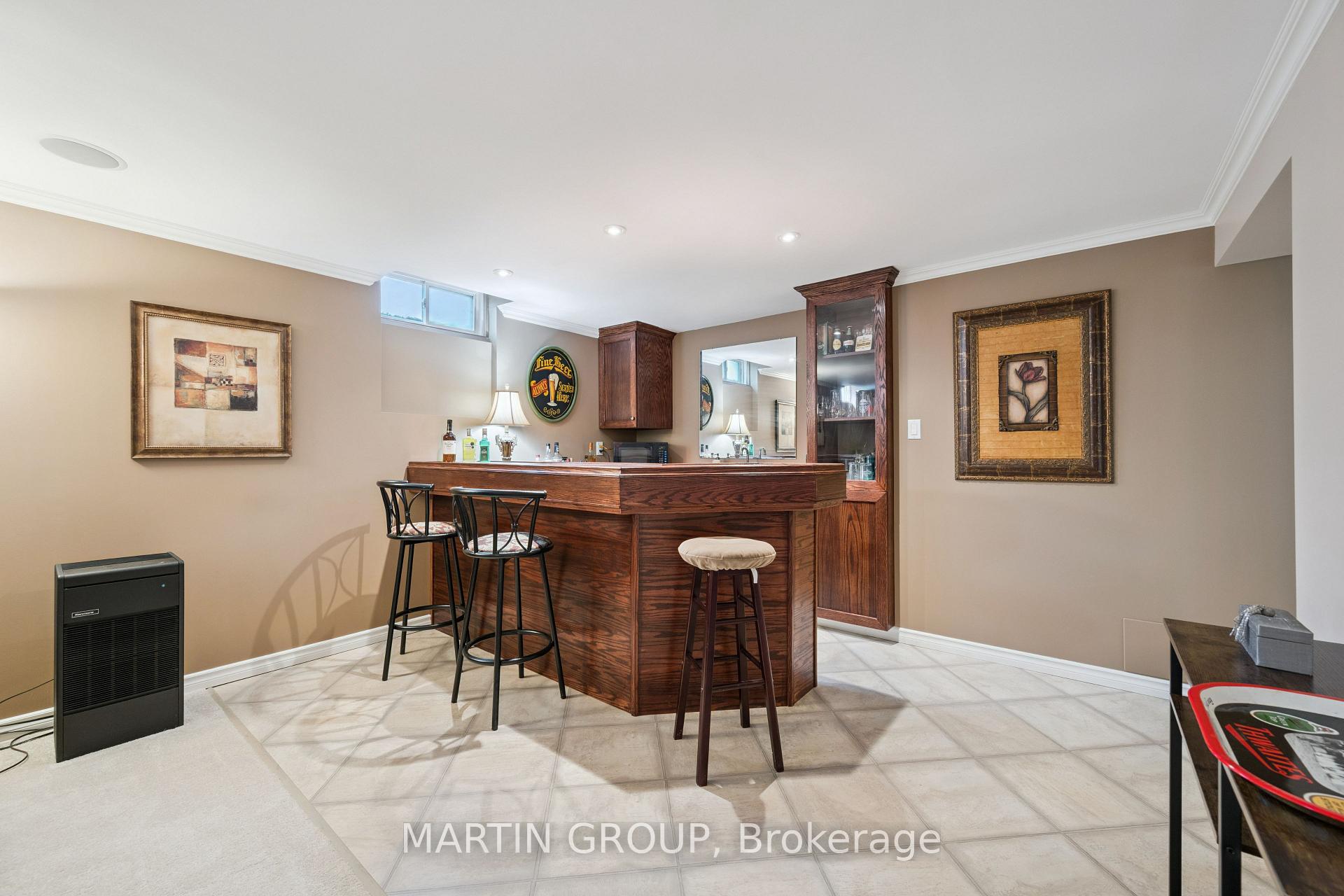 Basement bar with a large dark wood counter, stools and built-in glass-front cabinets.
