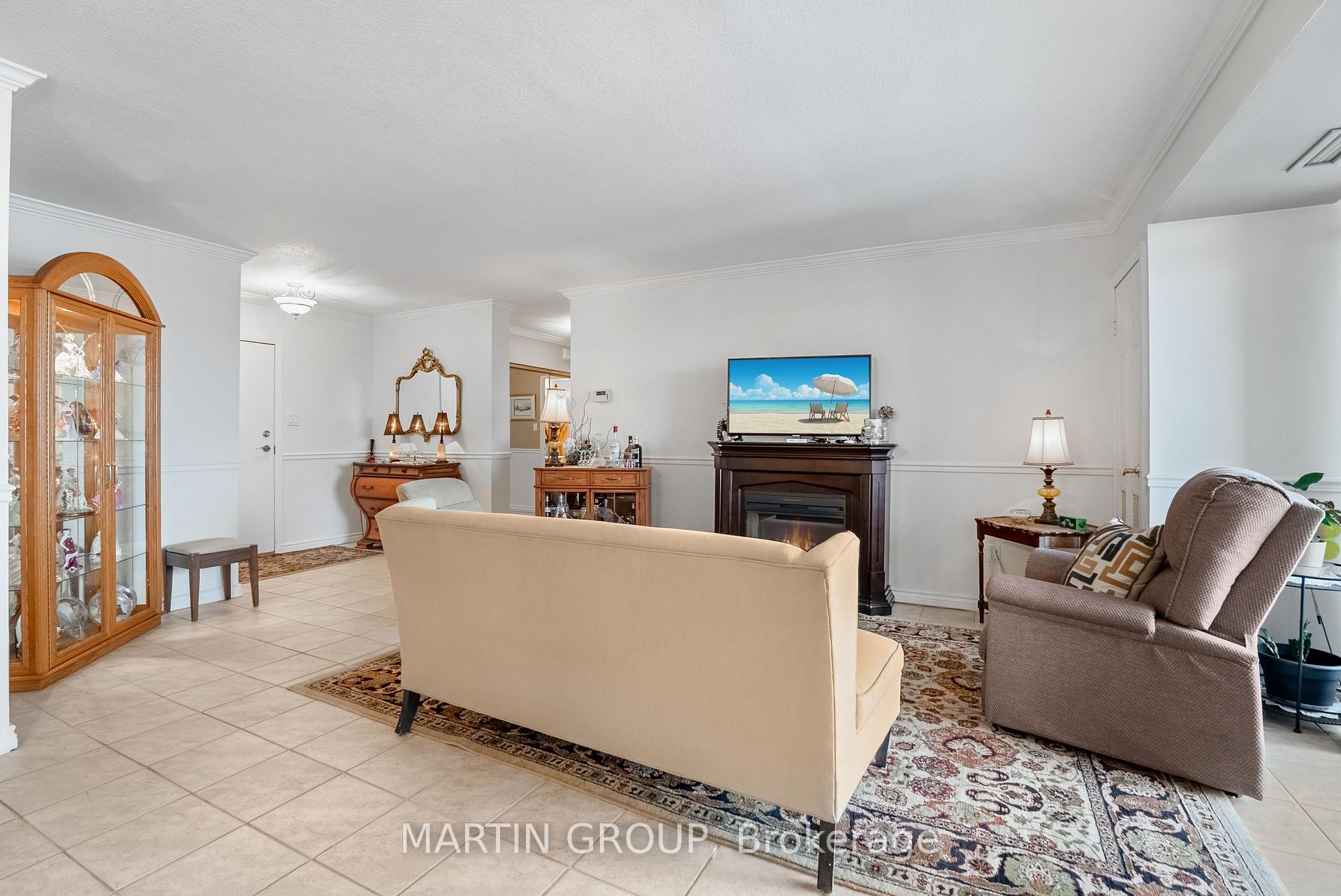 Furnished living room with a dark fireplace, cream sofa, and glass display cabinet.