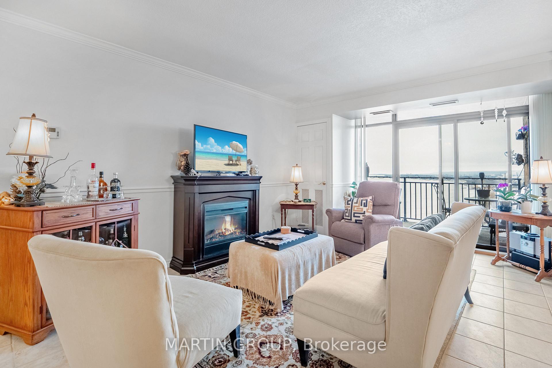 Living room with a fireplace, cream seating, and balcony doors overlooking the water.
