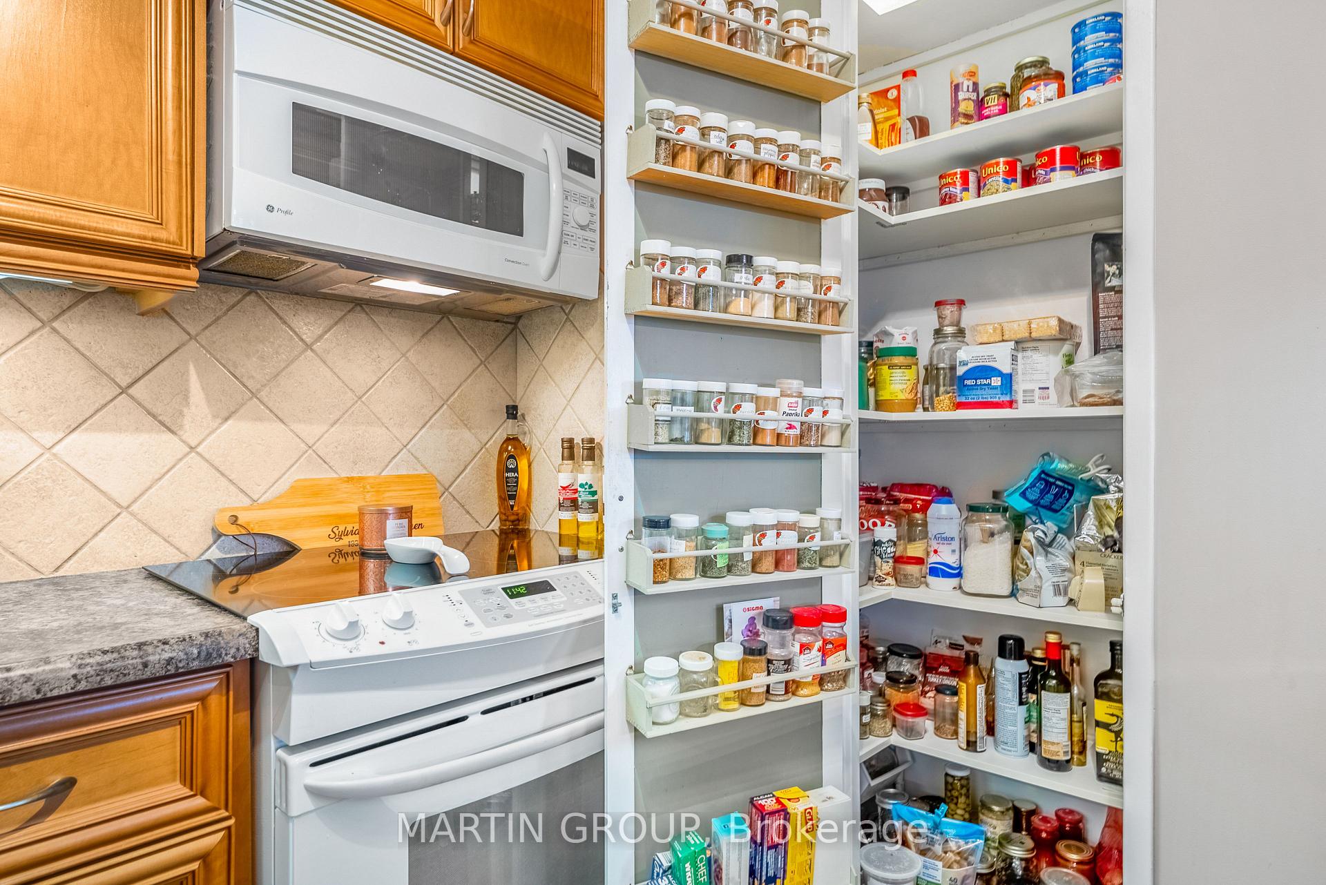 Kitchen with an open, well-stocked pantry beside a white range and microwave.