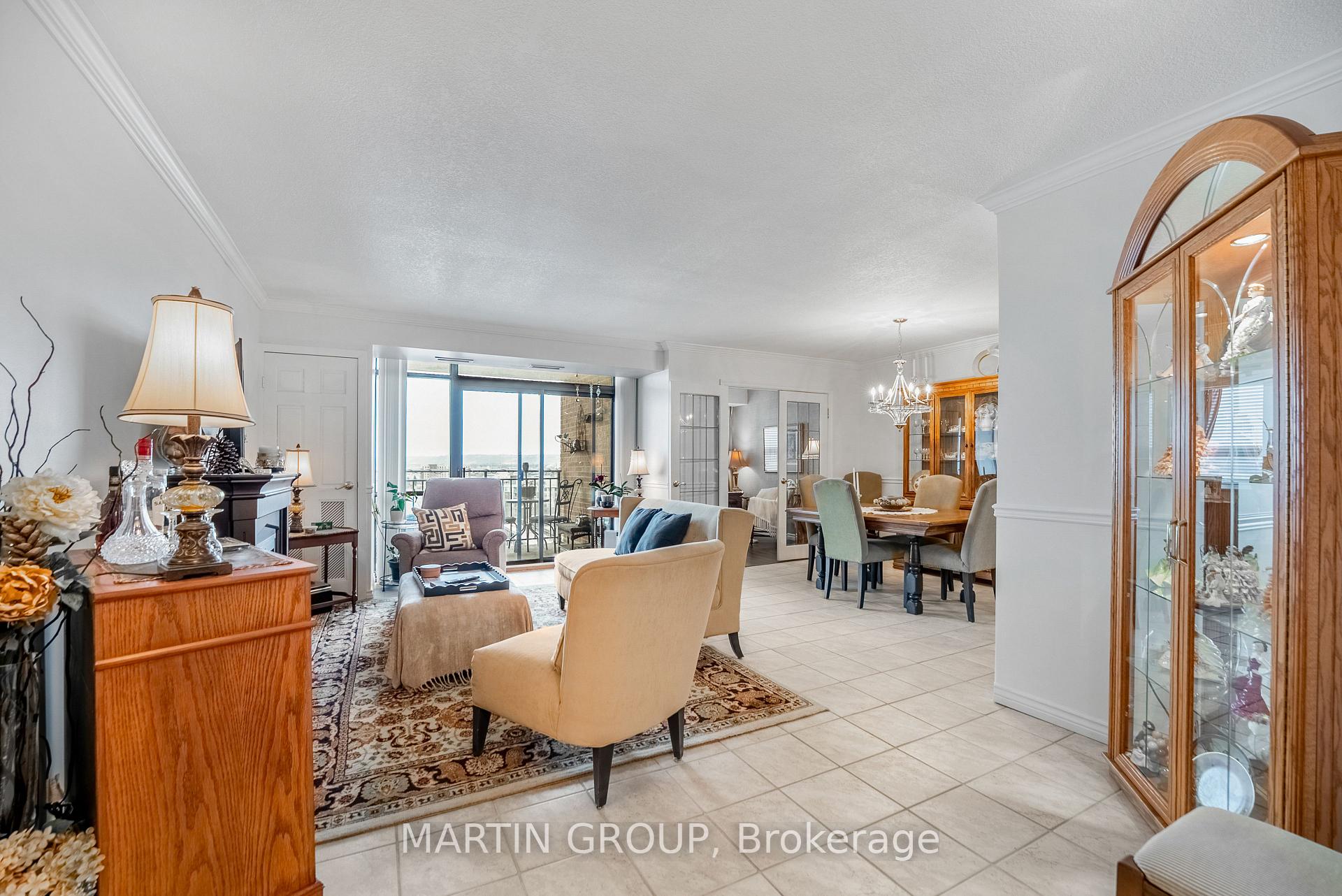 Furnished condo living and dining room with sliding doors to a balcony and distant water view.
