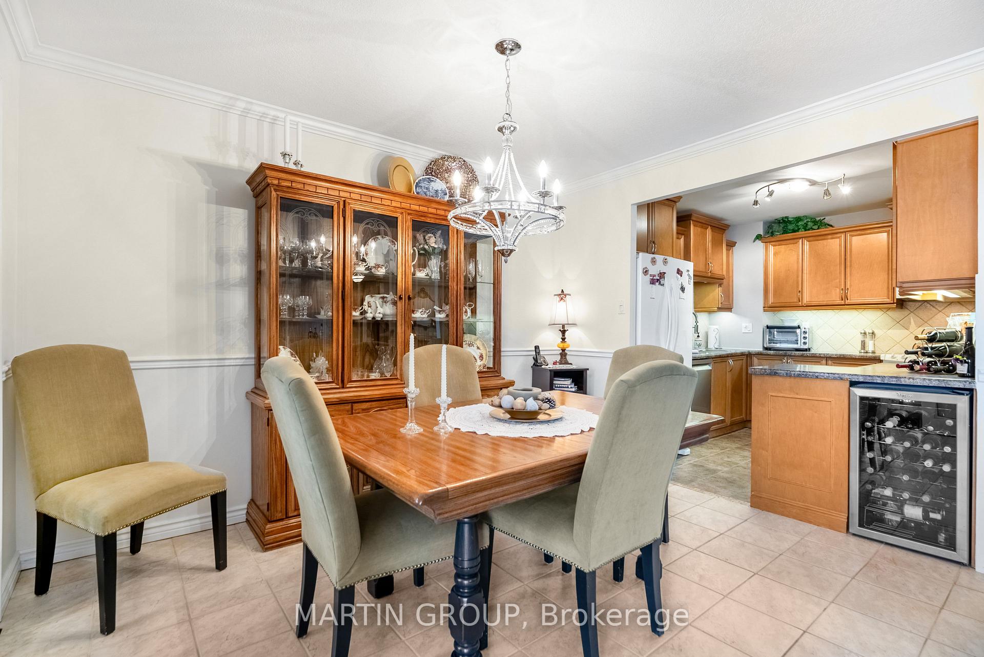 Dining room with a wooden table and china cabinet beside an open kitchen with wood cabinetry.