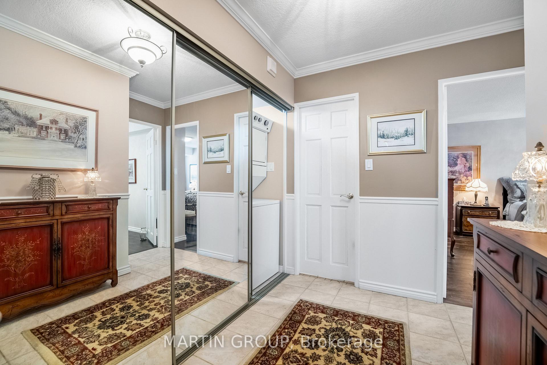 Bedroom dressing area with mirrored closet doors, tiled floor, and adjoining furnished bedroom.