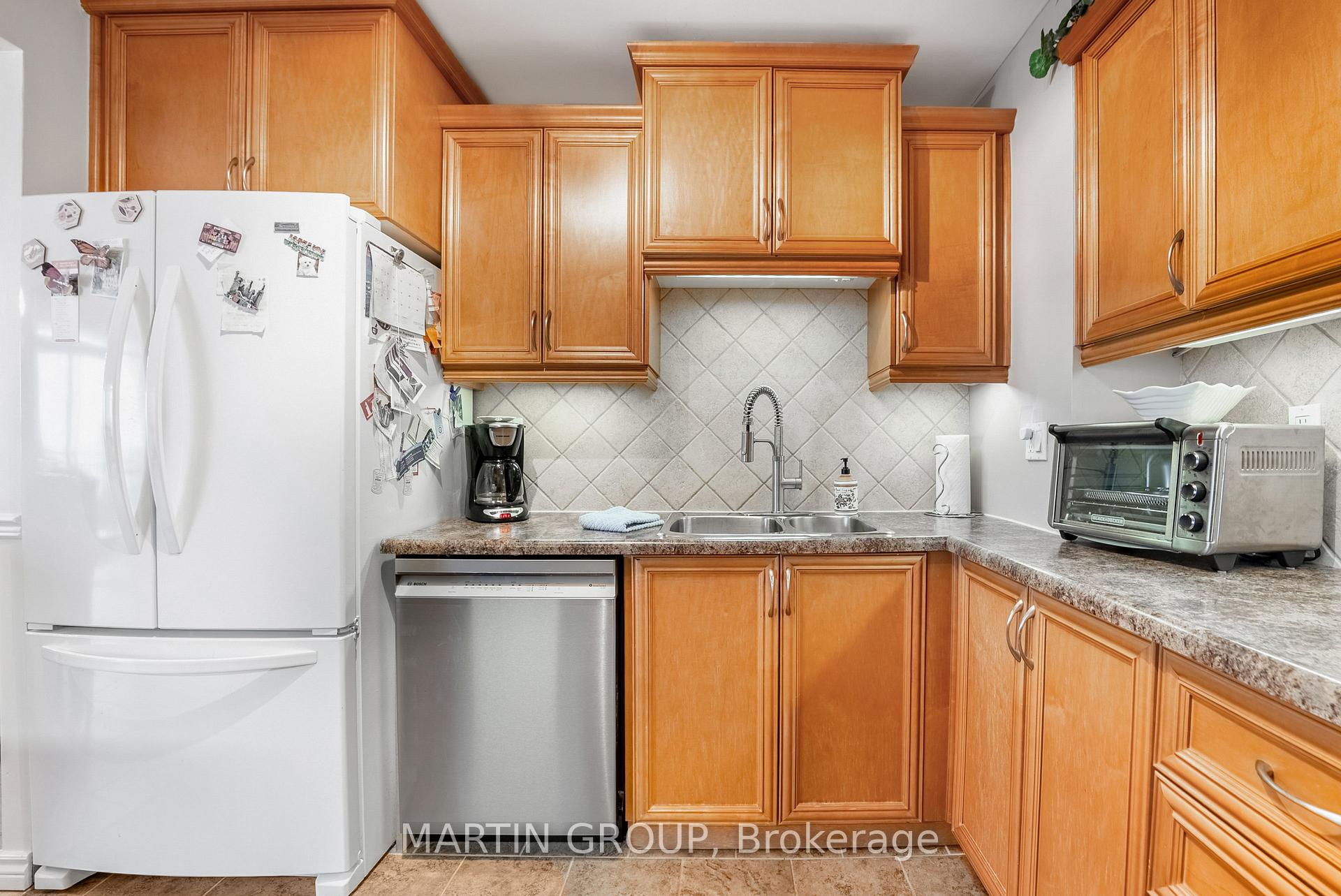 Kitchen with honey-colored wood cabinets, diagonal tile backsplash, and a double sink.
