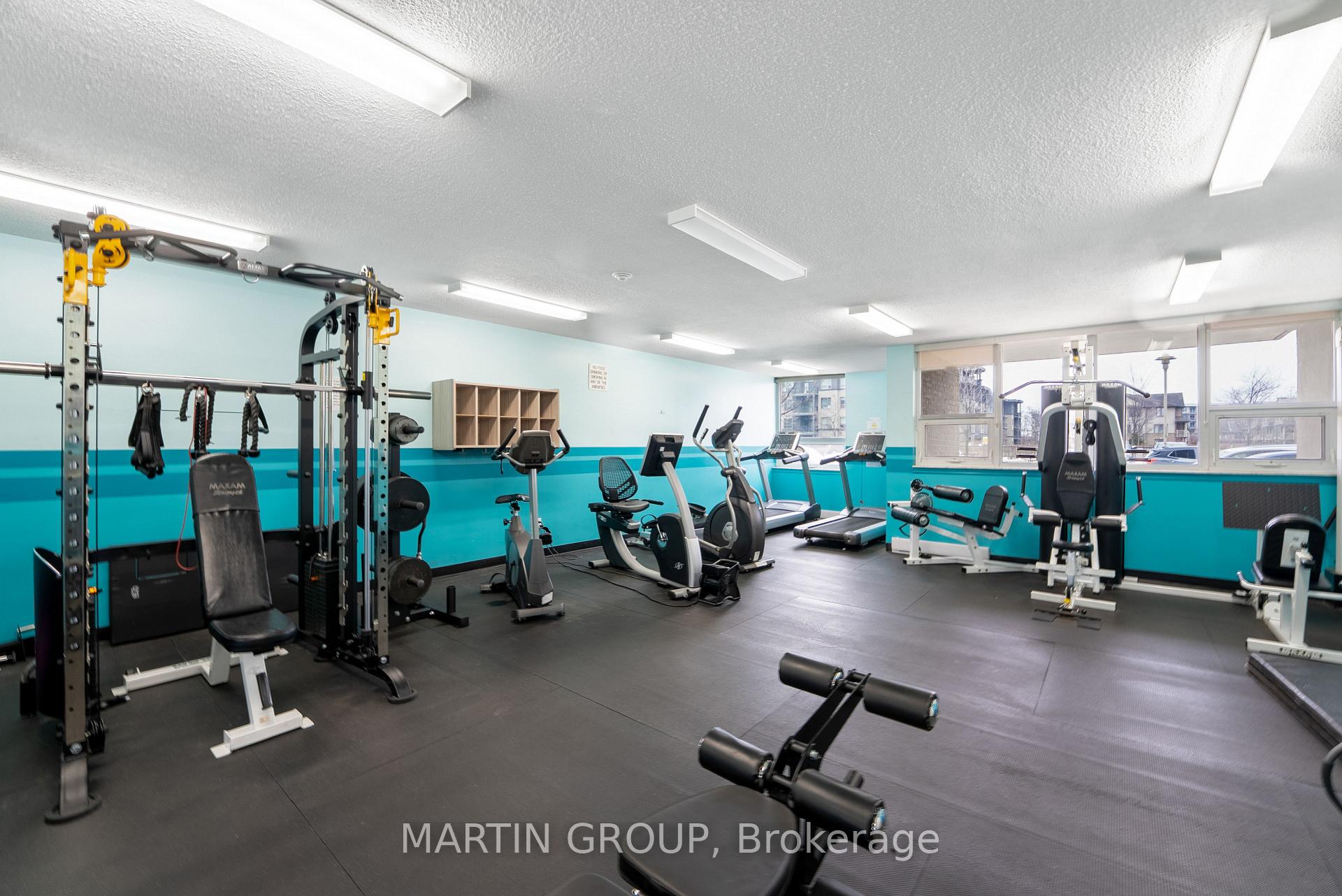 Condominium gym with weight machines, treadmills, and turquoise walls.