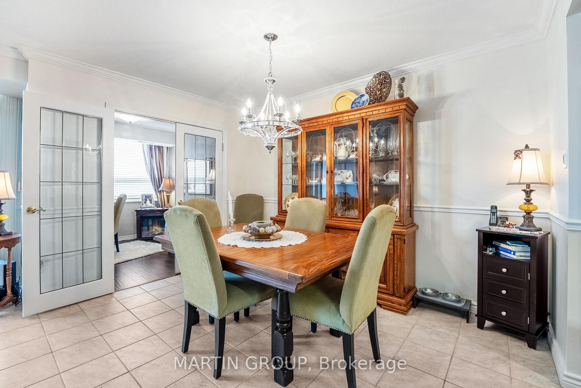 Dining room with a wooden table, green chairs, glass-front china cabinet, and chandelier.