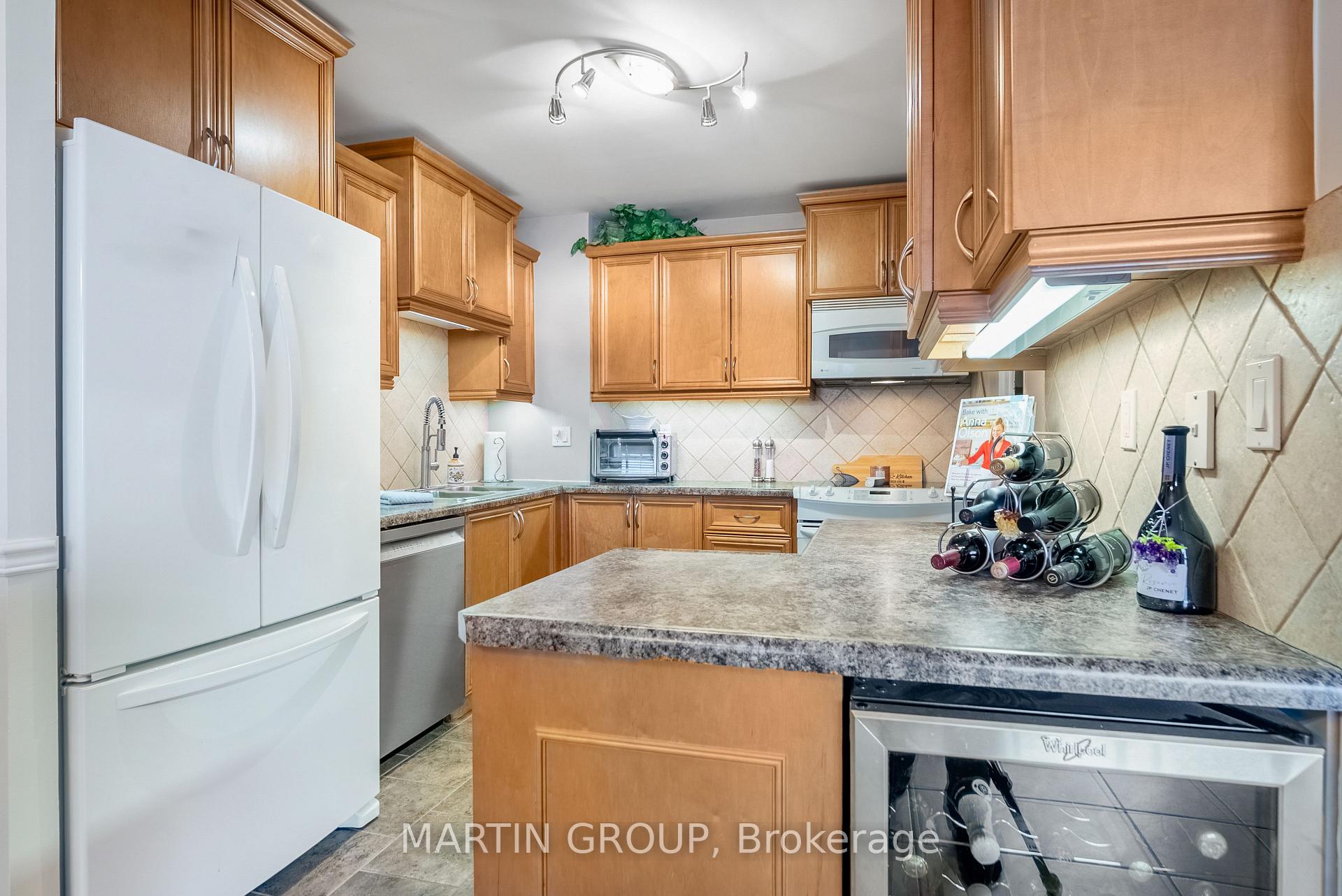 Kitchen with honey-toned cabinets, a large island, white refrigerator, and countertop wine rack.