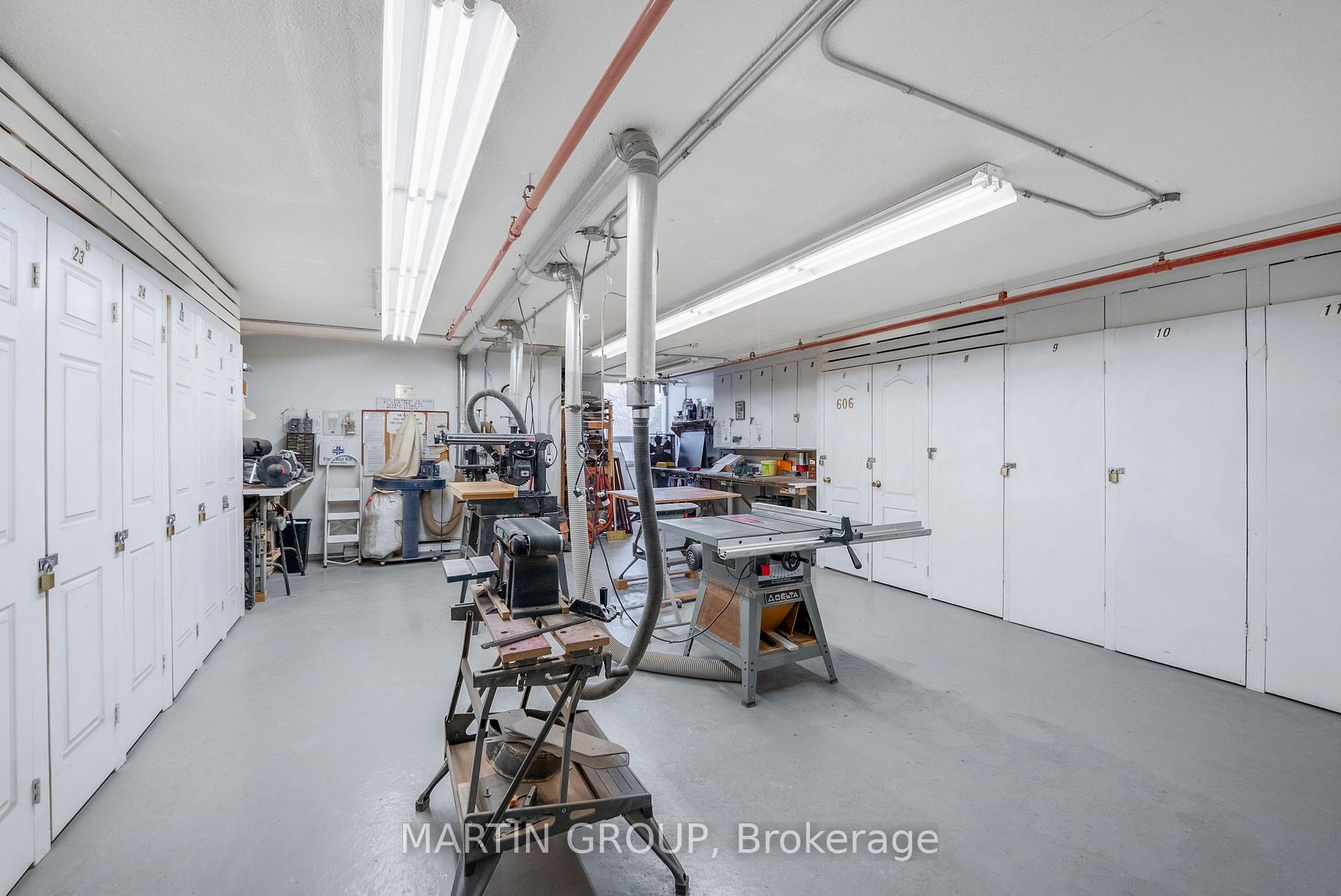 Woodworking workshop with numbered lockers, table saws, and dust-collection equipment.