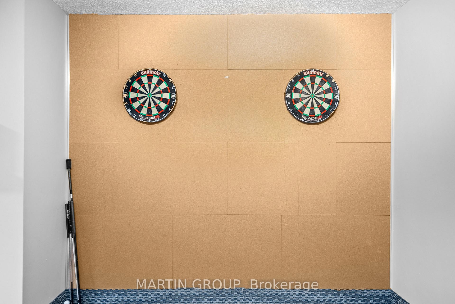 Recreation room with two dartboards on a cork-paneled wall and darts leaning in the corner.