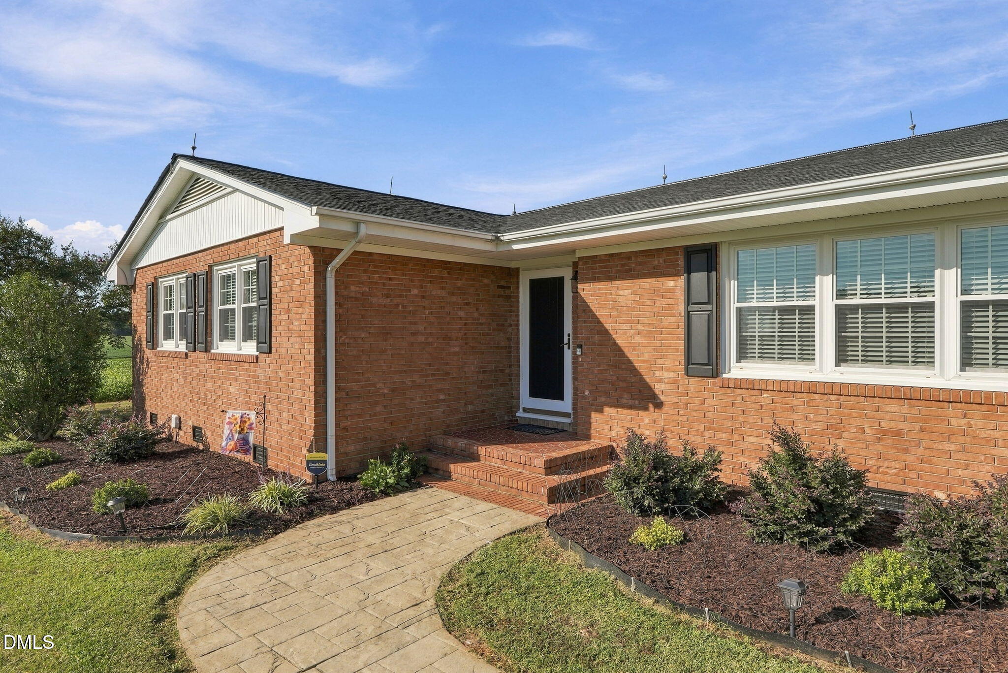 Red brick house with a recessed entry, landscaped beds, and a curved stone walkway.