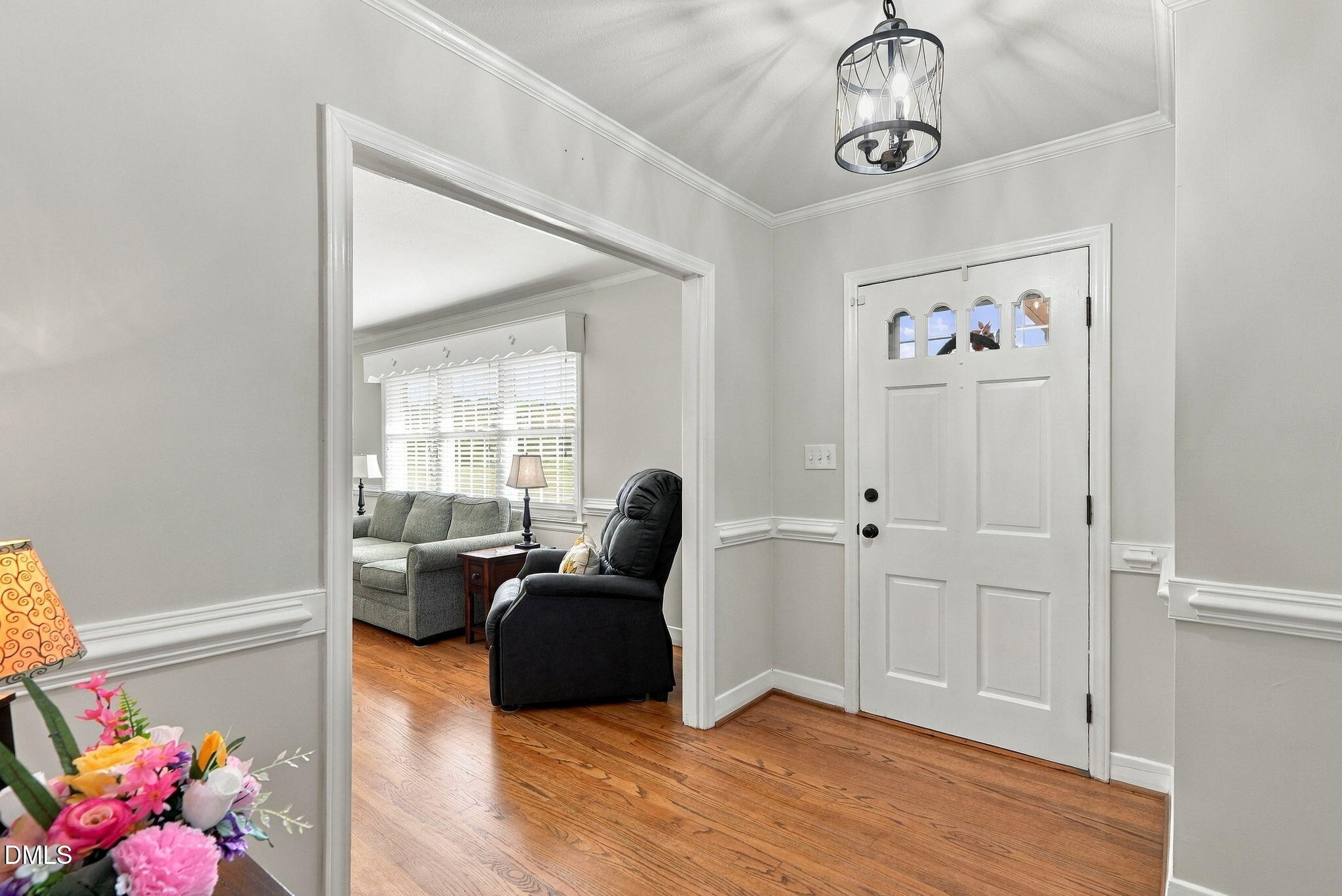Entryway with a white front door, hardwood floors, and a view into a furnished living room.