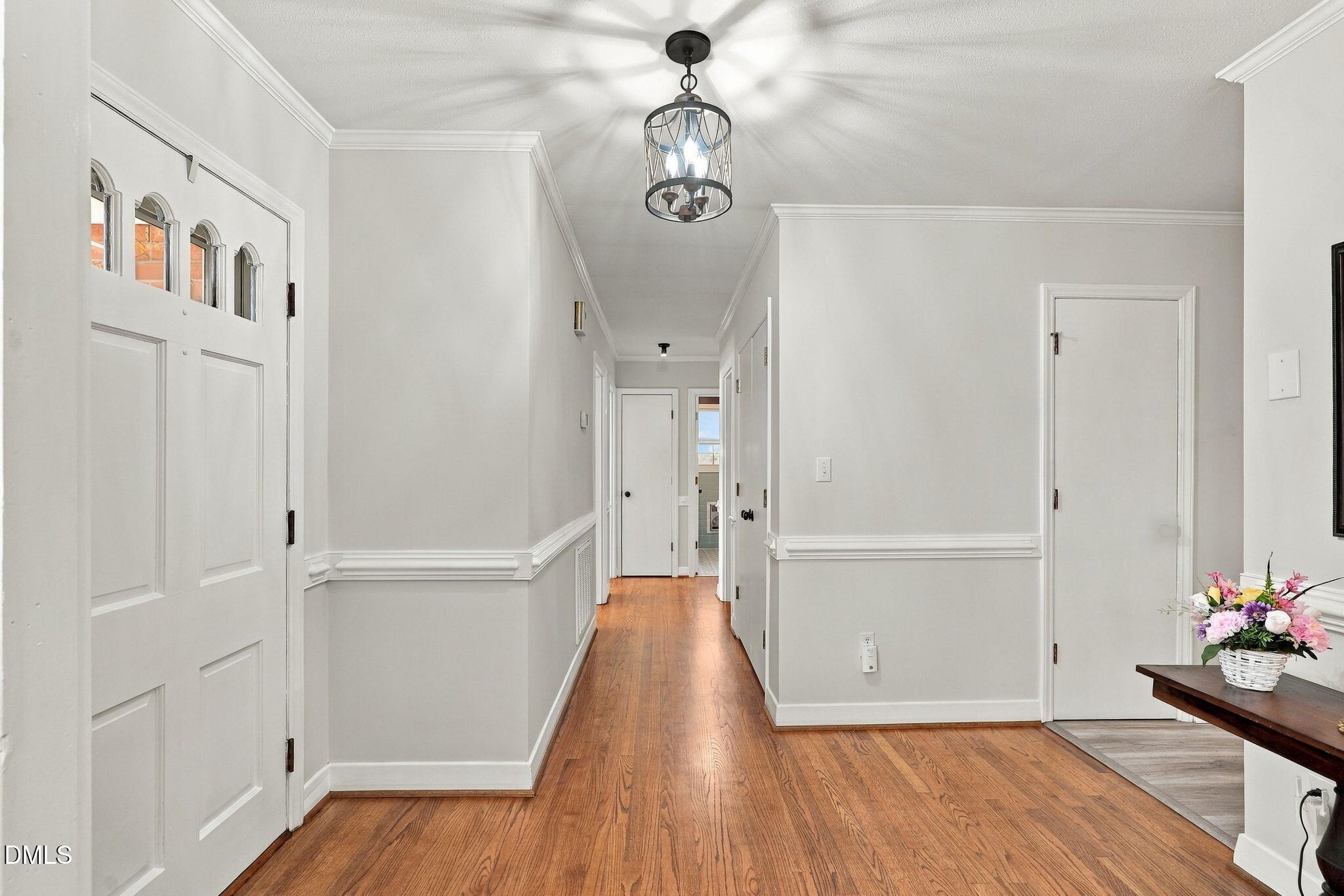 Entry hall with hardwood floors, arched-glass front door, and a lantern-style ceiling light.