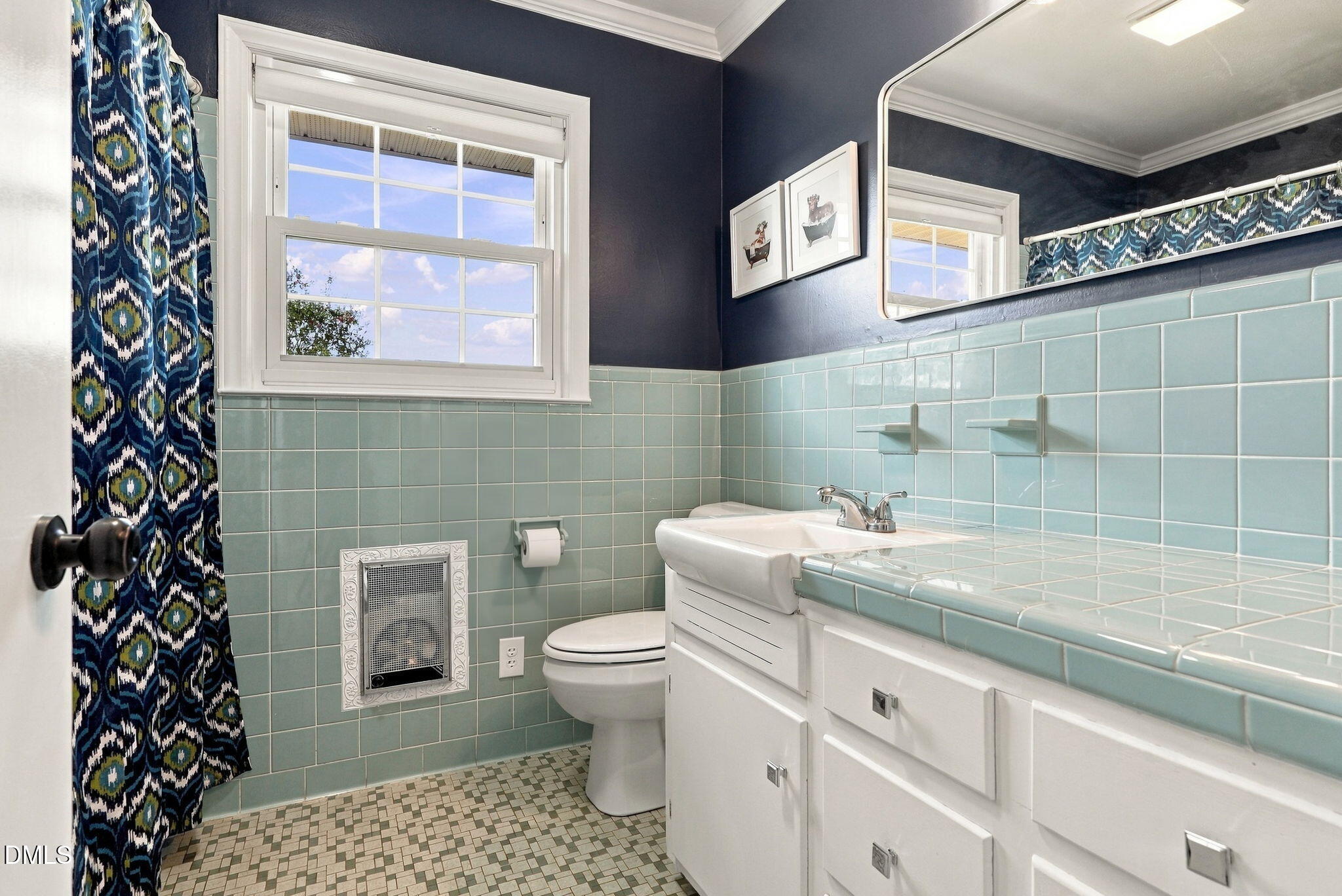 Bathroom with aqua tile, a white vanity, mosaic floor, and patterned shower curtain.