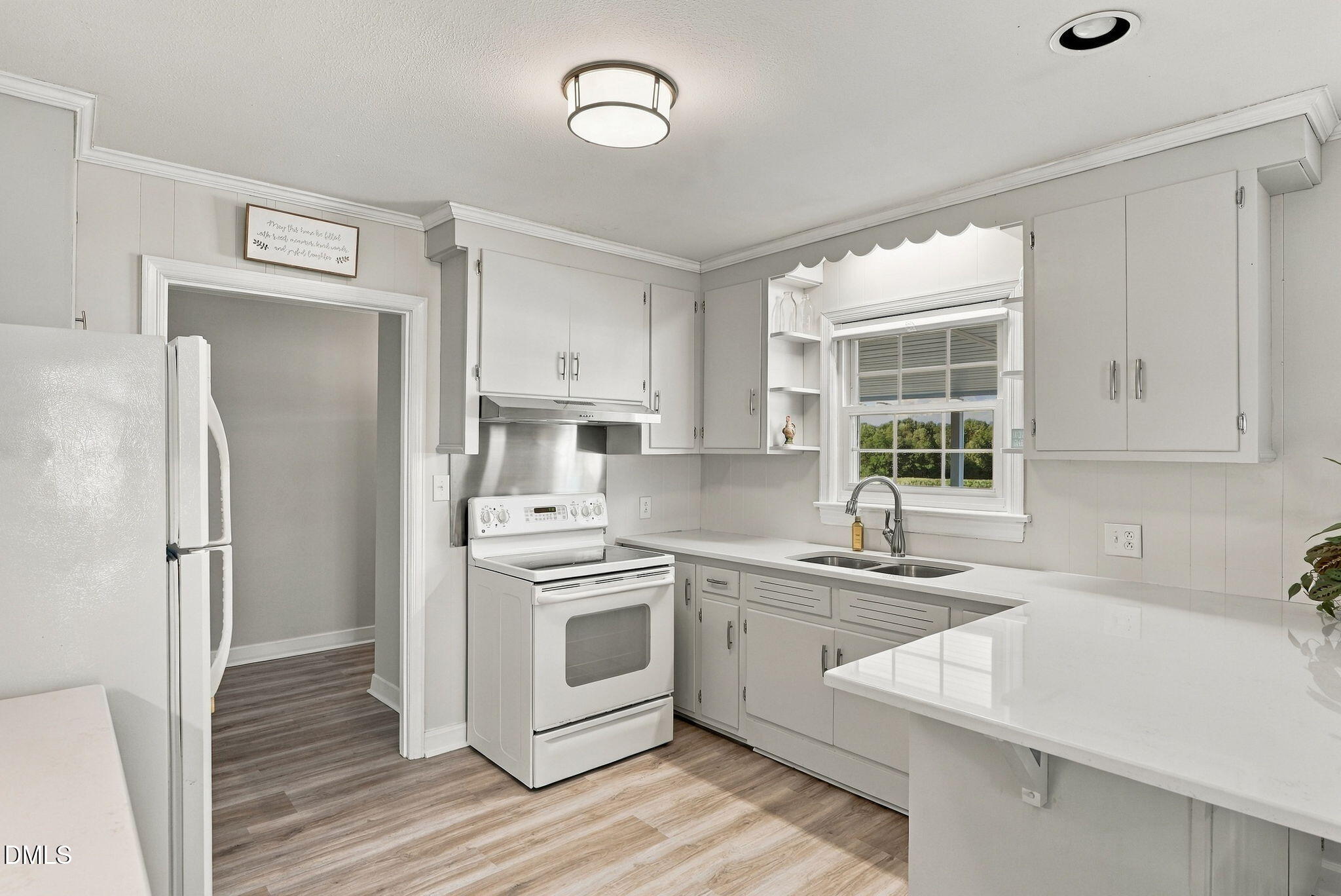 White kitchen with extensive cabinets, a window over the sink, and a glossy peninsula countertop.