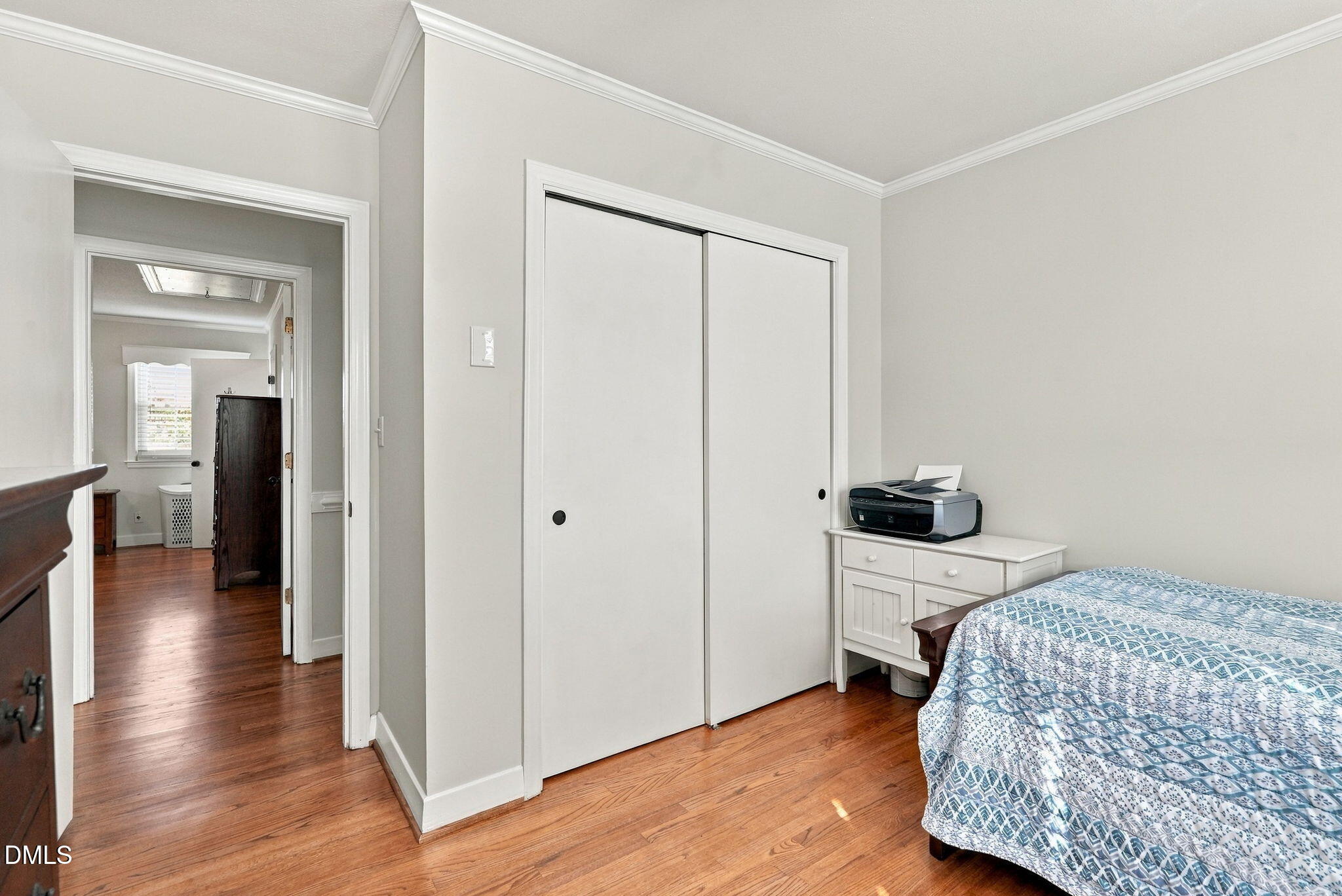 Bedroom with hardwood floors, white sliding closet doors, and a bed with blue patterned bedding.