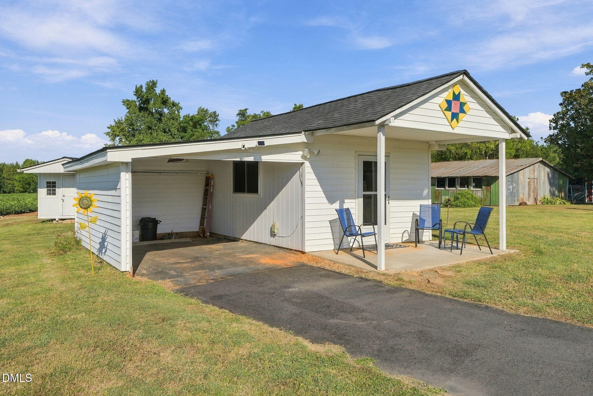 White building with an open garage, covered patio, and colorful quilt-pattern decoration on the gable.